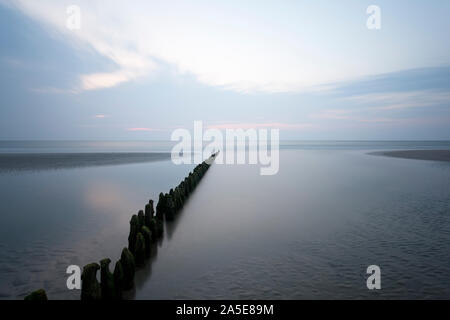 Une ligne de poteaux qui mène à la mer du Nord en Norderney, Allemagne. L'exposition à long shot. Banque D'Images