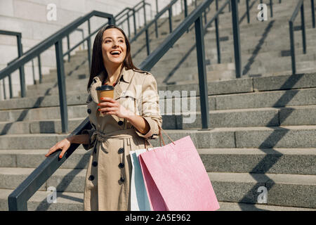 Ravi young woman holding tasse de papier dans la main gauche, tournant la tête à Sun Banque D'Images