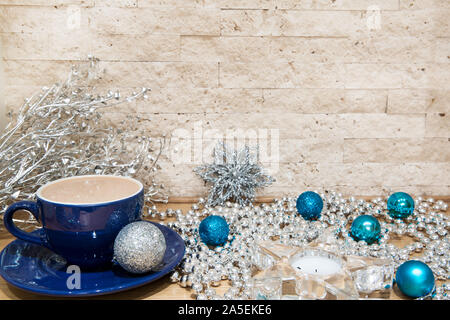 Sex cacao avec du lait en bleu tasse. Argent et bleu décorations de Noël, comme l'argent perles et boules de Noël. Chandelier en verre en forme d'étoile. Banque D'Images