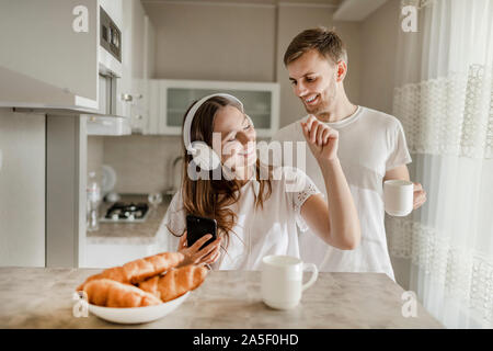 Couple aimant passer leurs matin par une tasse de café, de croissants et de la musique Banque D'Images