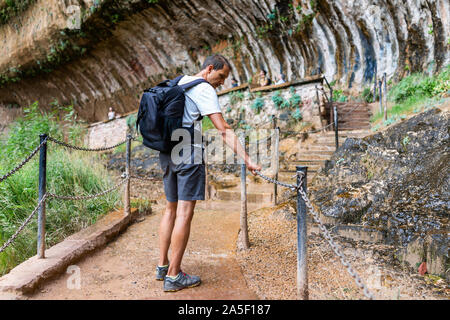 Zion National Park en Utah avec l'homme marche sur sentier de weeping rock à cascade et formations en été Banque D'Images