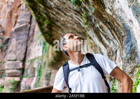 Zion National Park en Utah avec hiker man looking up permanent, sous sentier de weeping rock waterfall et formations en été Banque D'Images