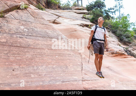 Zion National Park en Utah sur Gifford Canyon trail avec des formations de grès rouge et l'homme hiker wave rock escalade en été Banque D'Images