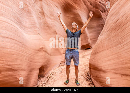 Homme heureux randonneur avec bras levés par des formations en forme de vagues rouge à l'emplacement de l'Antilope Canyon en Arizona sur sentier sentier du lac Powell Banque D'Images