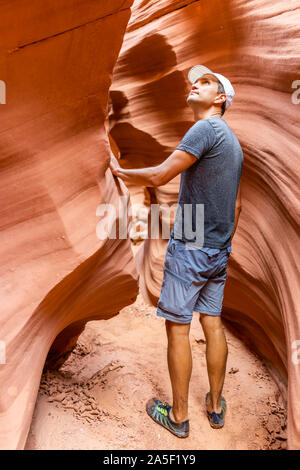 Formations en forme de vagues rouge-orange avec man walking touchant à la sauvegarder à l'emplacement de l'Antilope étroit canyon en Arizona sur le chemin du lac sentier sentier Banque D'Images