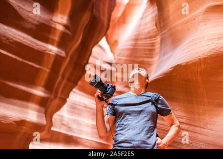 L'emplacement de l'Antilope canyon avec le photographe man holding à la caméra jusqu'au résumé des formations de roche de grès rouge orange couches en Page, Arizona Banque D'Images