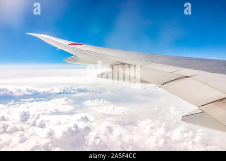 Narita, Japon - 27 mars 2019 : Avis d'aile d'avion par la fenêtre de vol au-dessus de nuages avec le ciel bleu et le cercle rouge symbole national du Japon Banque D'Images