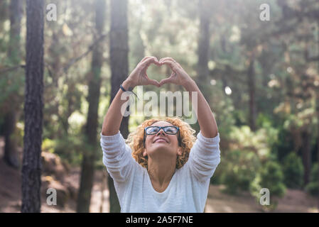 Respecter la nature en plein air et sauver les forêts concept monde avec belle femme adulte jusqu'à l'âtre et de faire l'amour signe avec ses mains - forest Banque D'Images