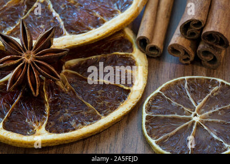 Tranches d'orange séchée et séchés tranche de citron avec des bâtons de cannelle et anis étoile sur fond de bois brun, Close up. Macro. Arrière-plan de l'humeur de Noël. Banque D'Images