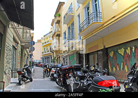 Athènes, Attique, Grèce - 17 octobre 2018 : les maisons ou appartements le long d'une rue étroite bordée de voitures et motos à Athènes, Grèce avec des niveaux inférieurs Banque D'Images