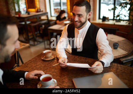 High angle portrait of businessman smiling barbu réussi heureusement tout en parlant de partenaire au cours d'affaires au cafe Banque D'Images