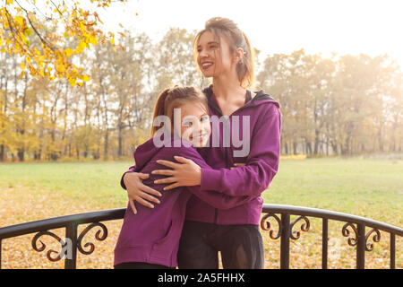 Loisirs de plein air. Soeurs article hugging in l'automne parc sur le pont de rire heureux Banque D'Images