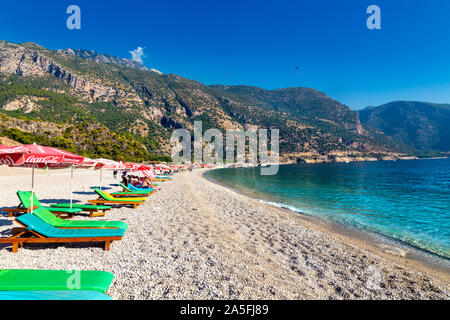 Plage de galets et de chaises longues avec des parasols à Oludeniz, Riviera turque, Turquie Banque D'Images