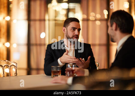 Portrait de deux business people talking while sitting at table in restaurant de luxe et de boire de l'alcool après le travail, copy space Banque D'Images