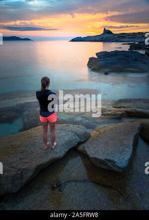 Woman standing on beach looking at view at sunset, Corse, France Banque D'Images