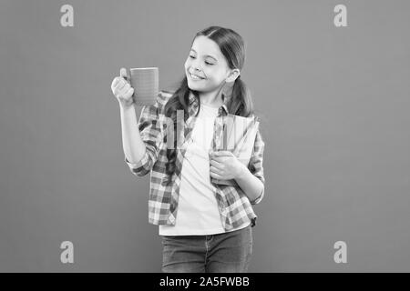 Dépenser temps agréable avec livre préféré. Fille tenir une tasse de thé et d'adresses. La littérature pour enfants. Aime passer du temps à la maison. Cacao chaud et bon livre idéal pour soirée agréable. Lecture bucket list. Banque D'Images