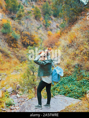 Female hiker walking in montagne forêt. Une femme avec un sac à dos est debout sur une grosse pierre dans les montagnes dans la forêt. Banque D'Images