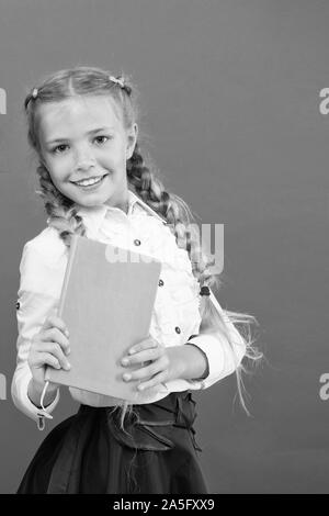 Si la connaissance dont vous avez besoin, vous devez lire. Cute little child holding livre sur fond rouge, petite fille avec réserve la connaissance dans les mains. Jour des connaissances ou le 1 septembre. L'accumulation de connaissances, l'espace de copie. Banque D'Images