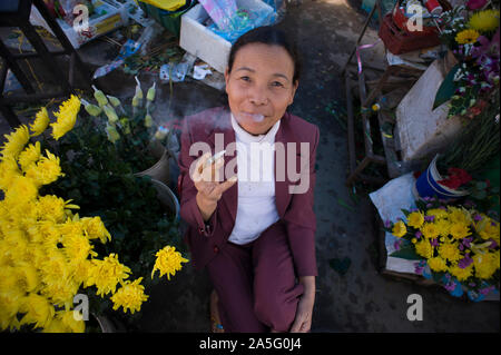 Ho Chi Minh Ville (Saigon), Vietnam - 27 Février 2011 : vendeuse de fleurs vietnamiennes avec anneau de doigt amputé de fumer une cigarette et souriant Banque D'Images