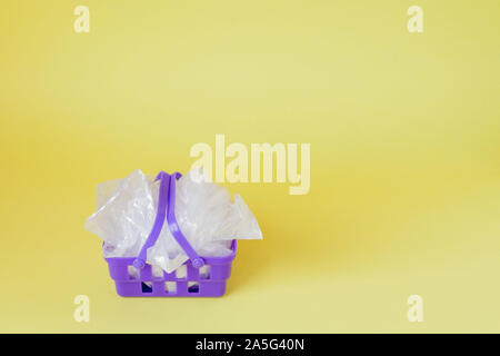 Sacs en polyéthylène dans panier sur fond jaune. Banque D'Images