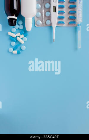 Traitement du rhume et de la grippe. Divers médicaments, un thermomètre, une pulvérisation d'une congestion nasale et une douleur dans une gorge sur un fond bleu. Copier l'espace. Medic Banque D'Images