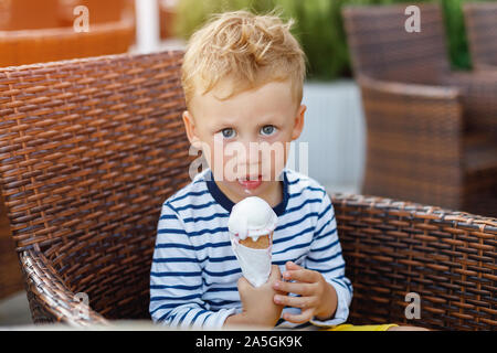 Cute kid boy eating ice cream dans street cafe Banque D'Images