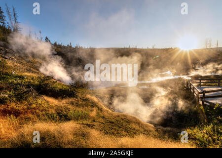 Coucher de soleil sur piste comme Paintpot Artistes passe de la vapeur les geysers et sources chaudes à Parc National de Yellowstone dans le Wyoming, USA. Banque D'Images