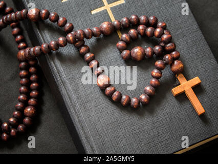 Chapelet en bois et Bible chrétienne sur une surface noire. Banque D'Images