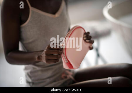 Femme afro-américaine tenant son sac à cosmétiques rose Banque D'Images