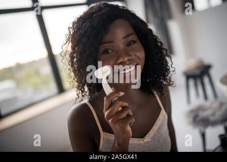 Cheerful basané woman cleaning sa peau le matin Banque D'Images