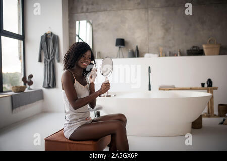 Smiling woman enjoying matin soins de beauté dans la salle de bains Banque D'Images