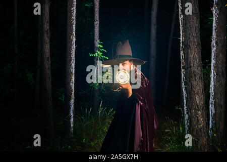 Fantasy wizard truc magique avec son bâton lumineux dans les bois lors de minuit Banque D'Images