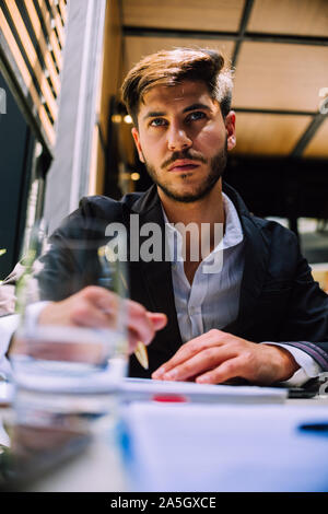Businessman la lecture d'un document. Jeune homme assis à son bureau en passant par un contrat Banque D'Images