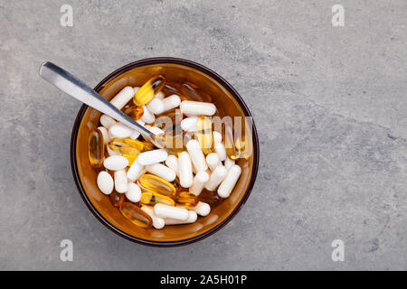 Comprimés, comprimés, capsules, les drogues en bol brun sur fond gris. Le sport, mode de vie sain, des médicaments, des suppléments nutritionnels, les gens - concept closeu Banque D'Images