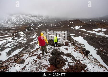 Randonneurs sur le sentier de randonnée alpine Tongariro Crossing dans la neige sur des champs de lave, Parc National de Tongariro, île du Nord, Nouvelle-Zélande Banque D'Images