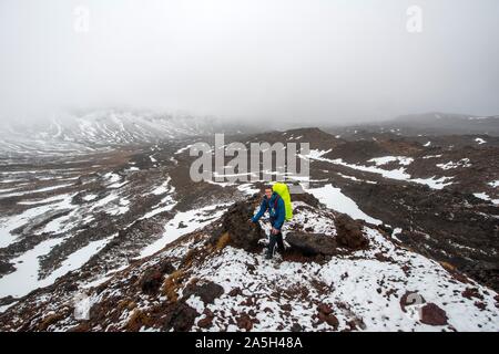 Randonneurs sur le sentier de randonnée alpine Tongariro Crossing dans la neige sur des champs de lave, Parc National de Tongariro, île du Nord, Nouvelle-Zélande Banque D'Images