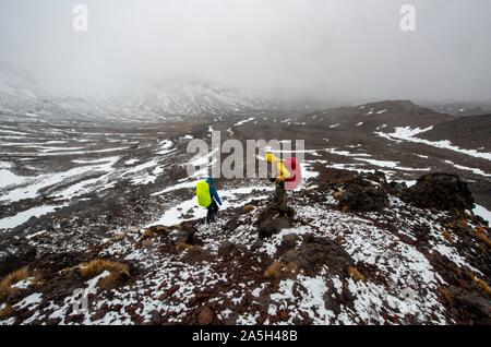 Randonneurs sur le sentier de randonnée alpine Tongariro Crossing dans la neige sur des champs de lave, Parc National de Tongariro, île du Nord, Nouvelle-Zélande Banque D'Images