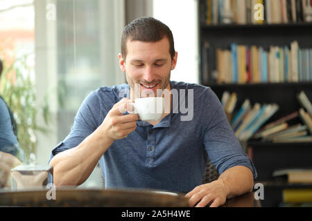 Vue de face d'un homme heureux savourer une tasse de café assis dans un bar Banque D'Images