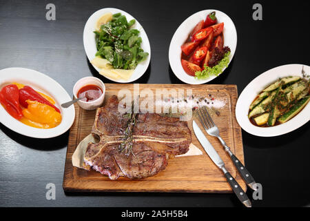 De délicieux steaks. Pavé de boeuf saignante sur coussin de légumes. Pavé de boeuf sur plaque de bois. Banque D'Images