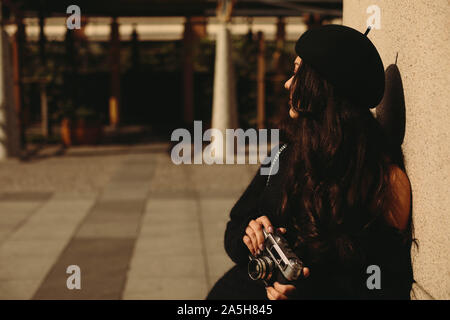 Woman in hat holding retro camera et prendre photo Banque D'Images