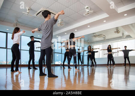 Groupe de danseurs debout à grande fenêtre en studio et répéter après mouvement femme avant Banque D'Images