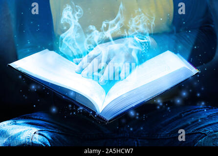 Les assistants sont des adolescents de l'incantation d'un sort d'un livre de magie,ont de la fumée et une lumière venant de sa main. Banque D'Images