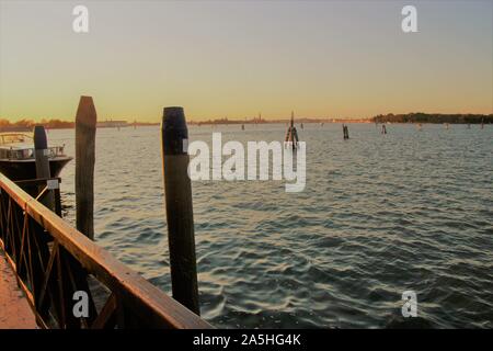 Vue sur la lagune de Venise au coucher du soleil, vu de l'île de Lido di Venezia. Poteaux en bois dans de l'eau, dans le contexte des petites îles. Italie,Europe Banque D'Images