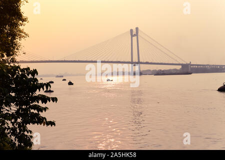 Coucher de soleil sur Vidyasagar Setu (un cantilever moderne Spar Cable-Stayed Bridge) dans une soirée d'été sur la rivière Hooghly. Vue de la lointaine Silhouette. Comment Banque D'Images