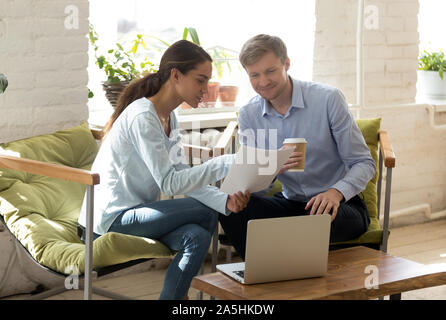 Deux collègues discuter divers smiling rapport de projet au bureau de coworking. Banque D'Images