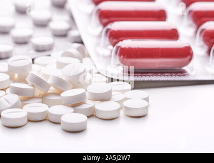 Still Life with pile ronde de pilules ou de comprimés antidépresseurs, analgésiques ou avec l'espace pour le texte. Capsules rouges en blister sur tableau blanc dessus. Banque D'Images