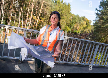 14 octobre 2019, Hessen, Frankfurt/Main : Katja Unterköfler (51) de l'administration des chemins de fer se distingue avec un plan de construction sur le pont à l'ancienne route (S-Bahn) à proximité de l'aéroport de Francfort. La ligne sera bientôt fermé et restauré à son état naturel. Les structures en béton et des ponts le long du parcours seront également supprimés. À l'avenir, les trains ne roulent plus de nouvelles pistes à la passerelle un arrêt de S-Bahn de jardins à l'aéroport. Photo : Frank Rumpenhorst/dpa Banque D'Images