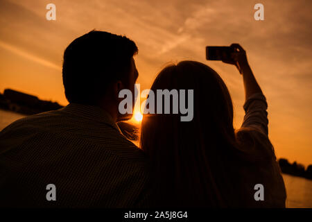 Heureux couple prend en selfies coucher de soleil dans la ville. Banque D'Images