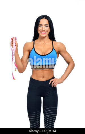 Portrait of happy smiling woman avec des cheveux noirs et de grands muscles. Célèbre et belle fitness trainer sportswear en posant à l'appareil photo. Athlète solide prêt pour mesurer son corps avant de la concurrence. Banque D'Images