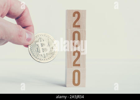 Tenir la main avec Bitcoin 2020 cubes en bois sur les numéros o avec un fond blanc. Le succès de l'évolution cryptocurrency dans la nouvelle année. Close up. Tonique Banque D'Images